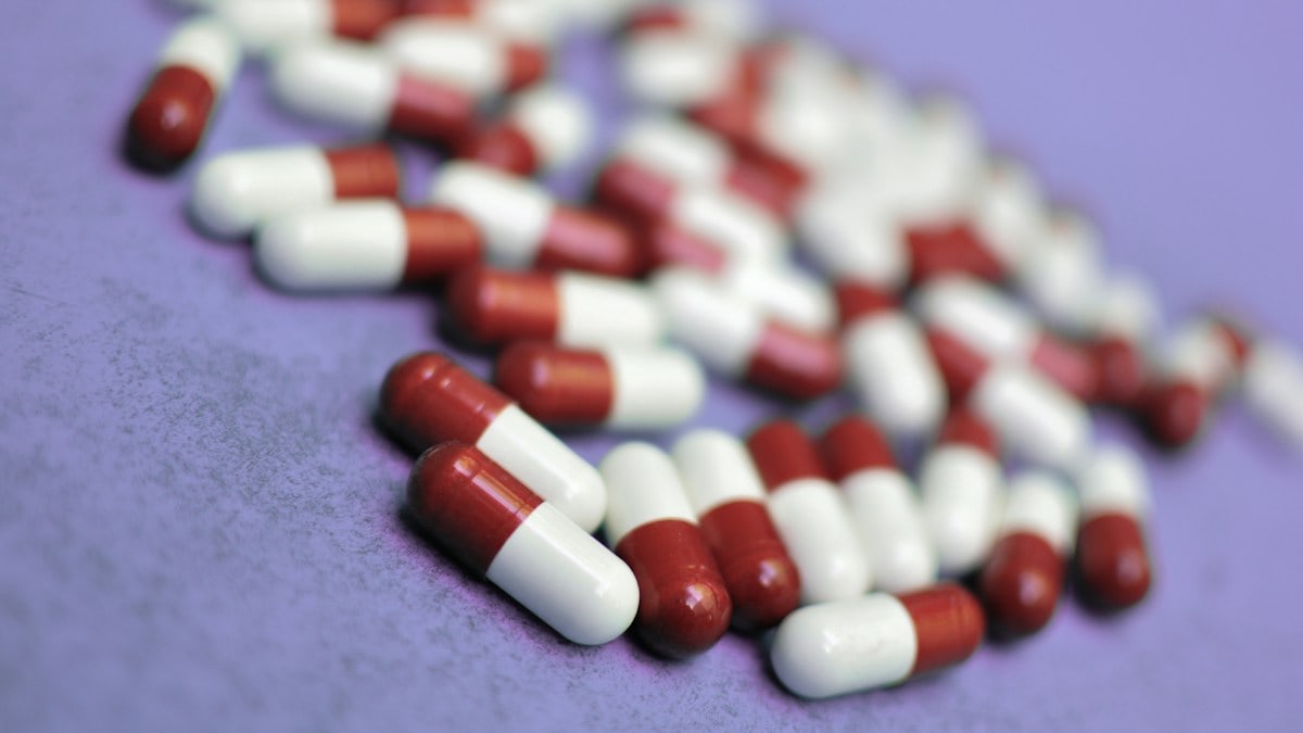 Pills are scattered on a purple surface
